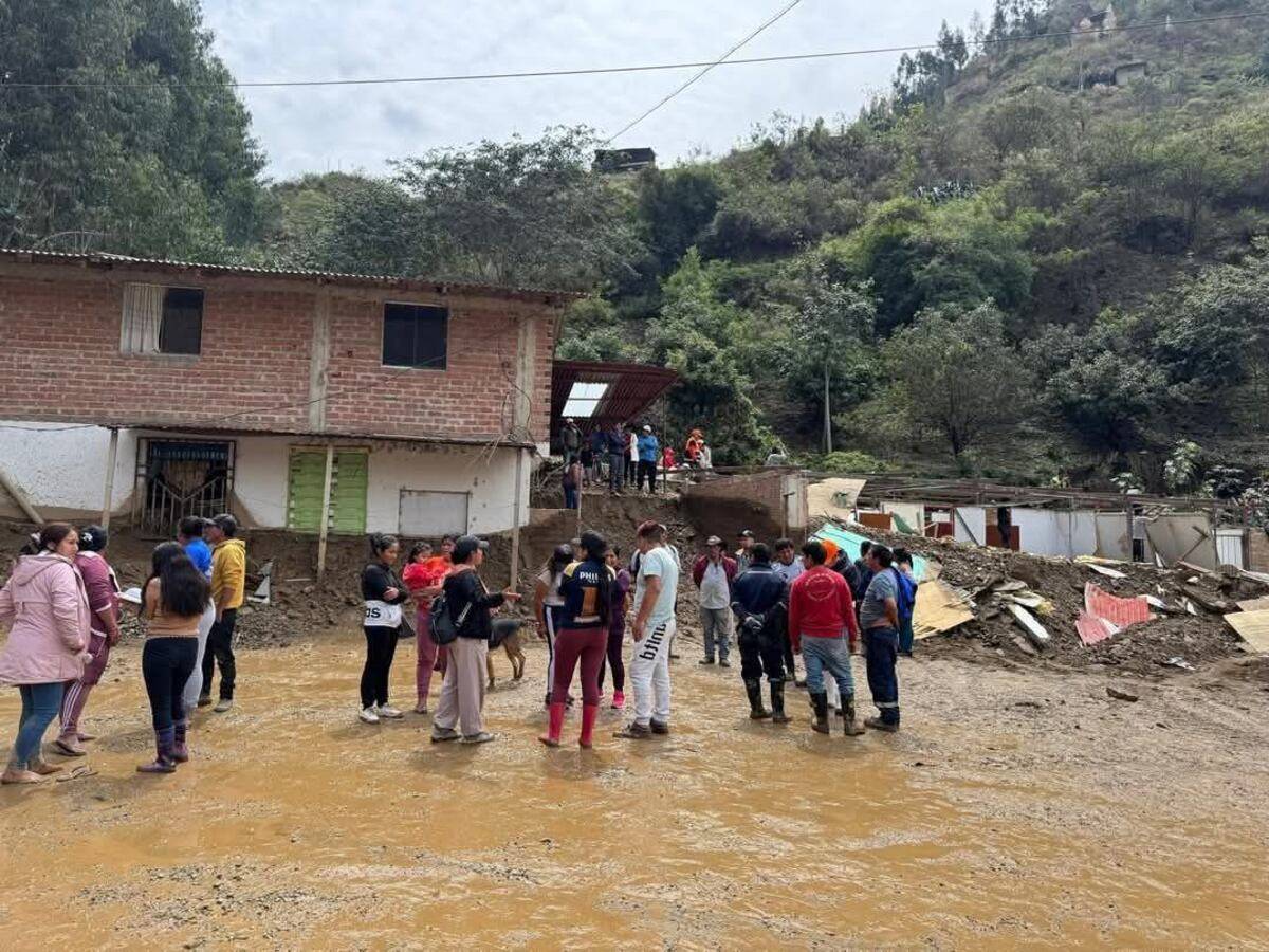 Vecinos evaluando daños en una calle cubierta de lodo tras un huaico