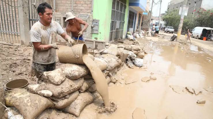 Vecinos retirando lodo y colocando sacos de arena frente a sus casas