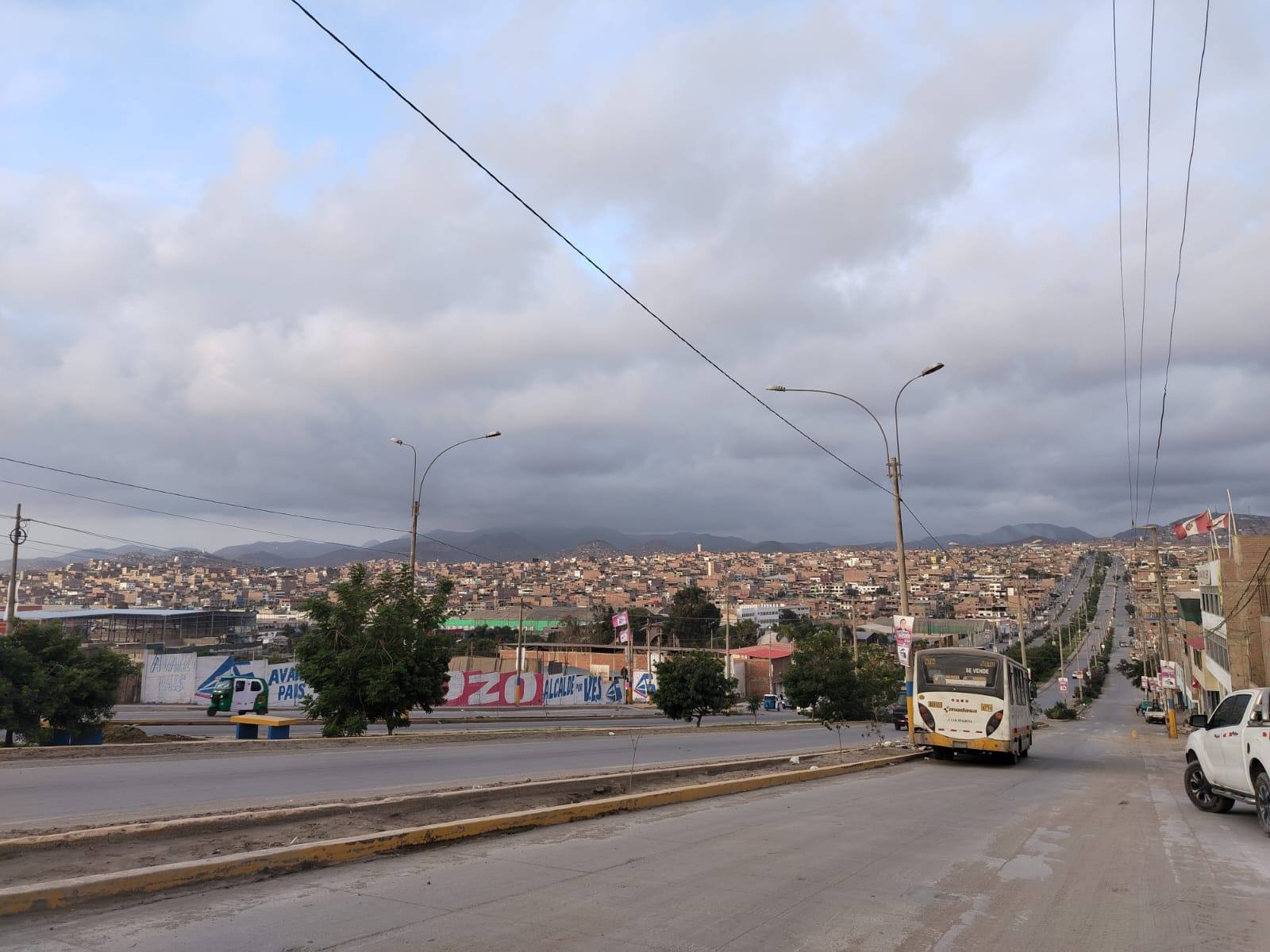 Avenida principal de un distrito de Lima con el barrio extendido hasta los cerros