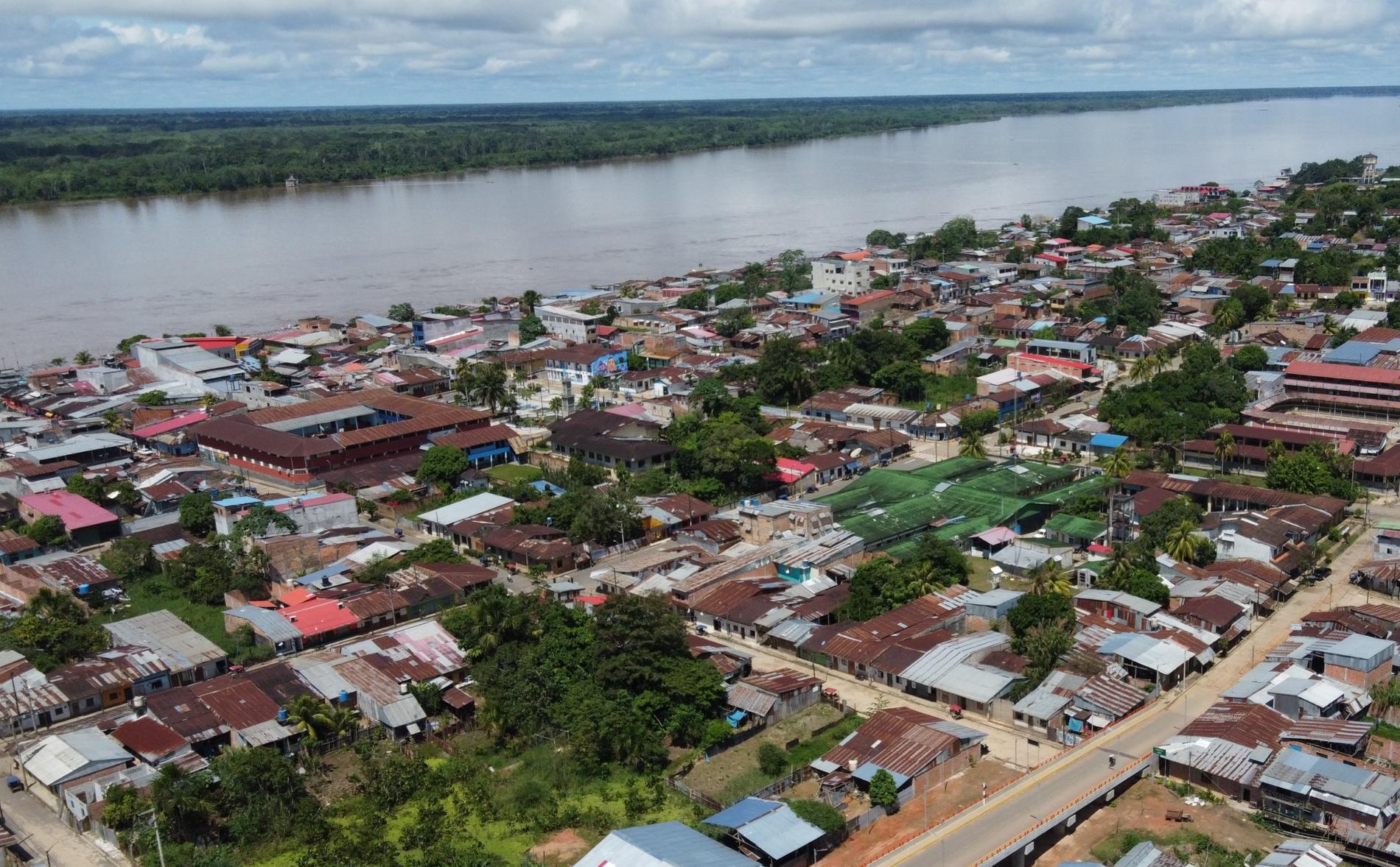 Vista aérea de una ciudad amazónica del Perú junto al río, con un nuevo puente vehicular