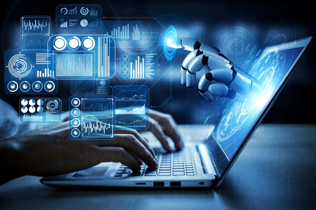 Manos sobre un computador portátil con paneles de datos y una mano robótica que señala un indicador