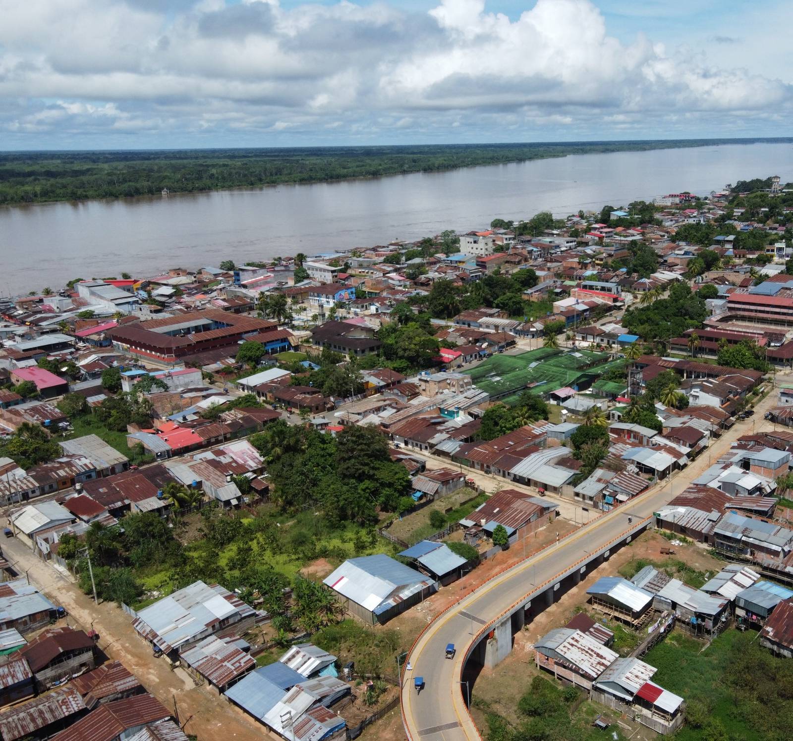 Vista aérea de una ciudad amazónica a orillas de un gran río, con un nuevo puente vehicular